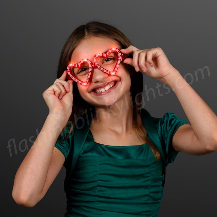 Girl wearing heart-shaped light-up candy cane glasses with red LEDs and no lenses.