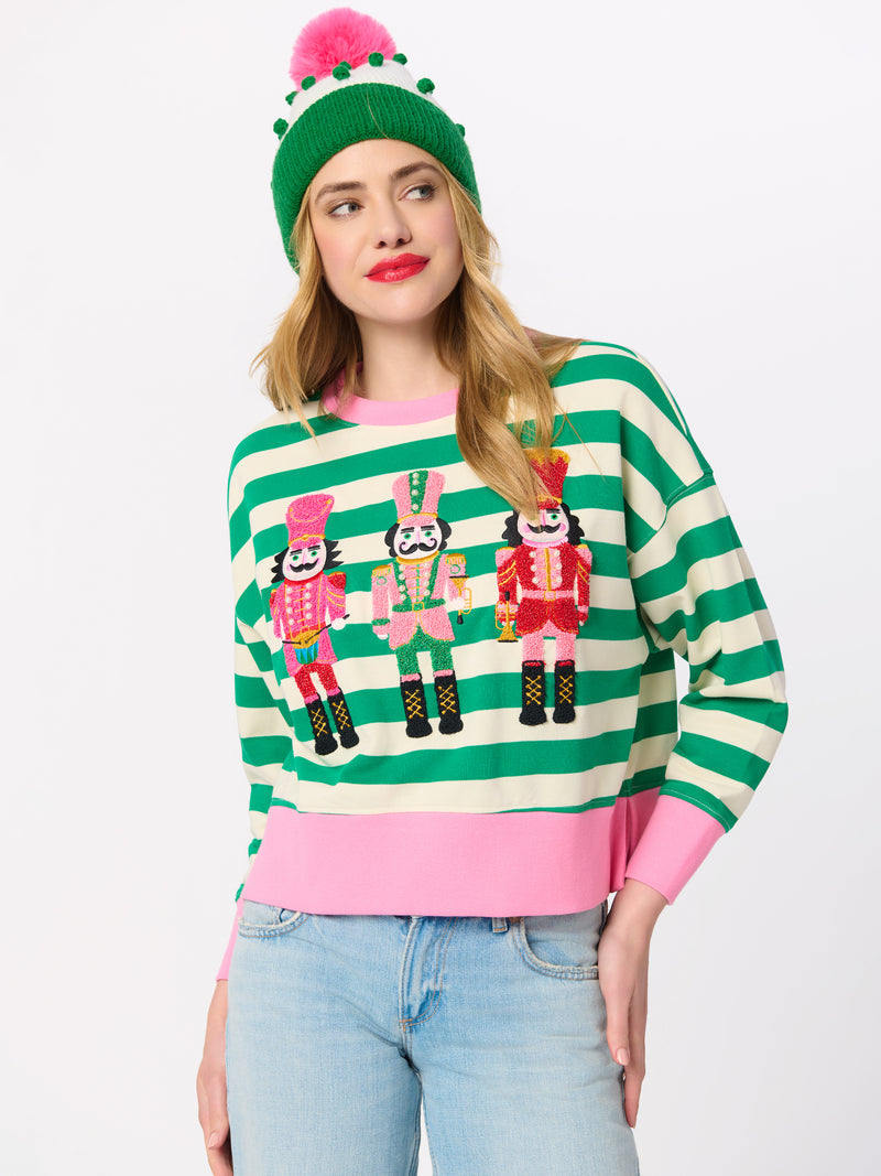 Woman wearing the Serena Nutcrackers Relaxed Sweatshirt with green stripes and pink accents.