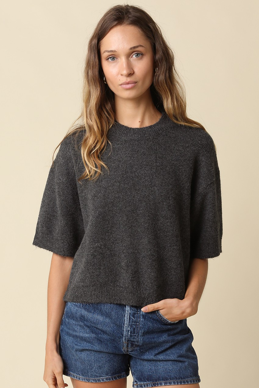 Woman wearing the Alice Parker charcoal grey half-sleeve sweater and denim shorts.