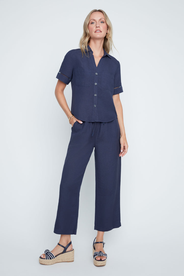 Woman wearing a navy blue short-sleeve Liza Woven Blouse and matching wide-leg linen pants.