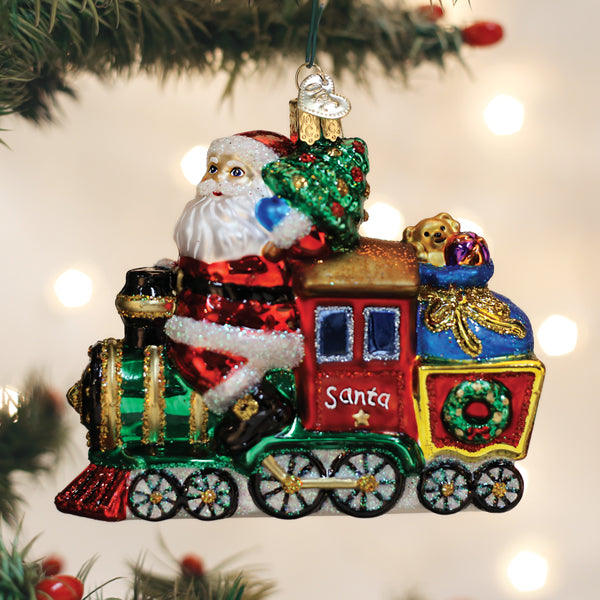 Glass Santa on Locomotive ornament with a Christmas tree and toy sack hanging on a tree branch.