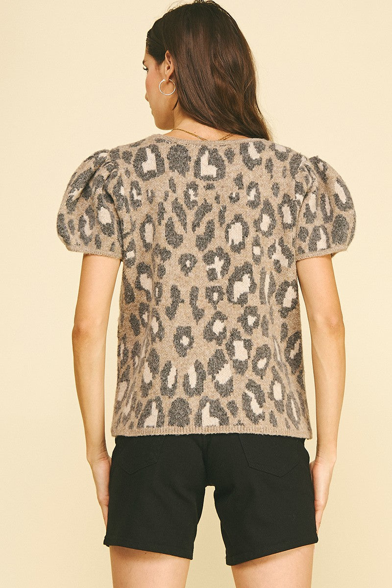 Back view of a woman wearing a tan and grey leopard print knit sweater with puff short sleeves.