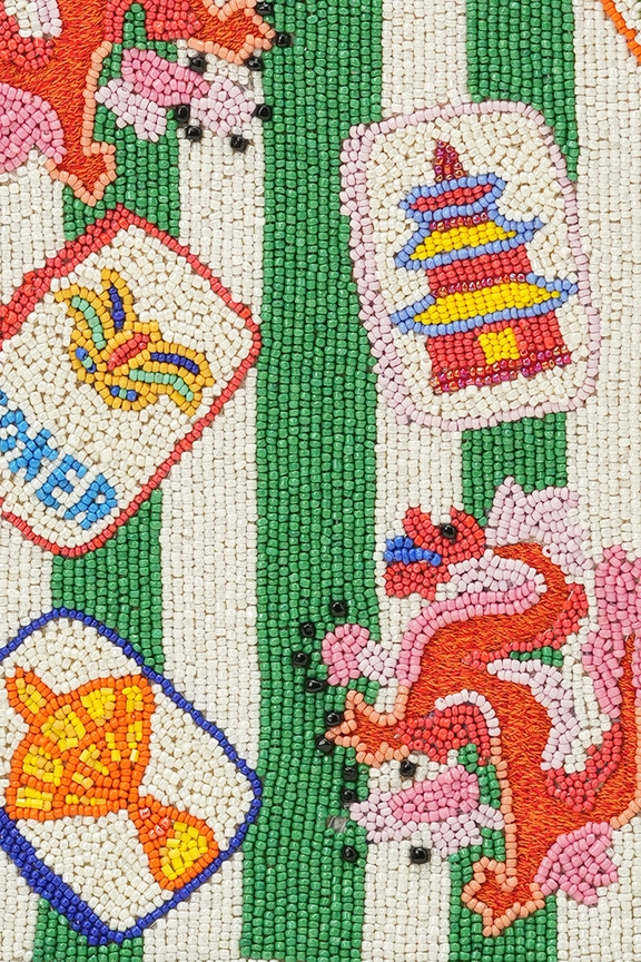 Close-up of hand-beaded mahjong tiles and dragon motifs on a green and white striped tote bag.