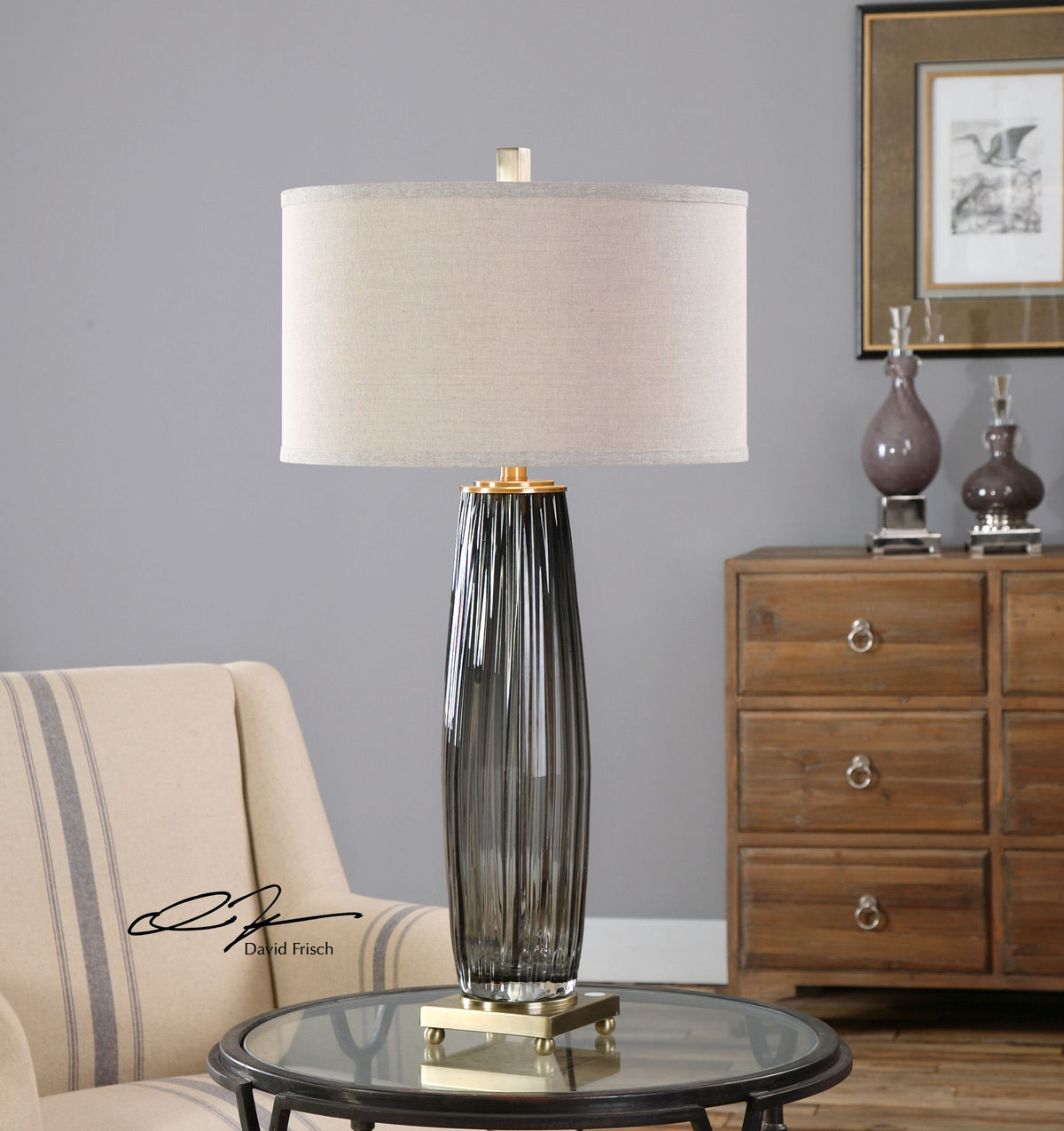 Gray glass table lamp with a cylindrical shade and minimalist metal base.