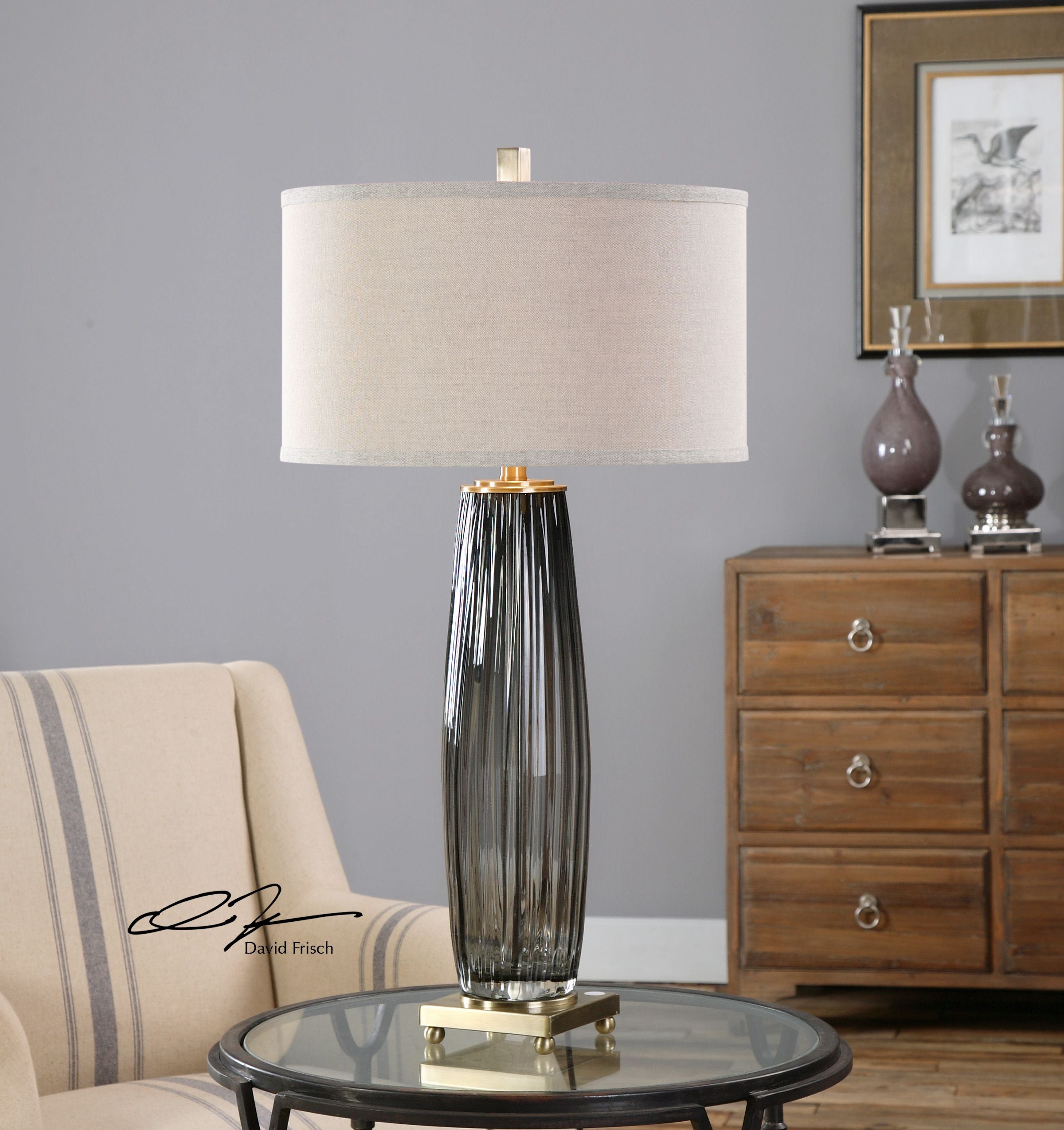 Gray glass table lamp with a cylindrical shade and minimalist metal base.