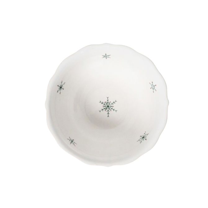 Top view of a white ceramic cereal bowl with green snowflake patterns and a scalloped rim.