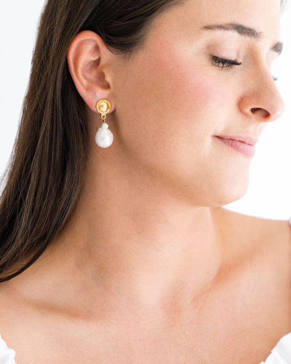 A woman wearing a Baroque Pearl Post Earring featuring a gold coin stud and a white drop pearl.