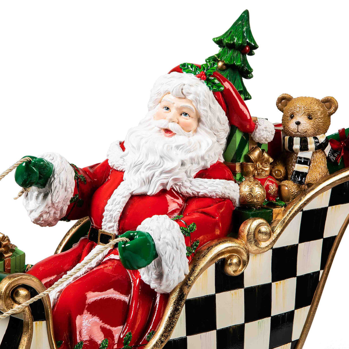 Santa in a checkered sleigh with a teddy bear, gifts, and a Christmas tree.