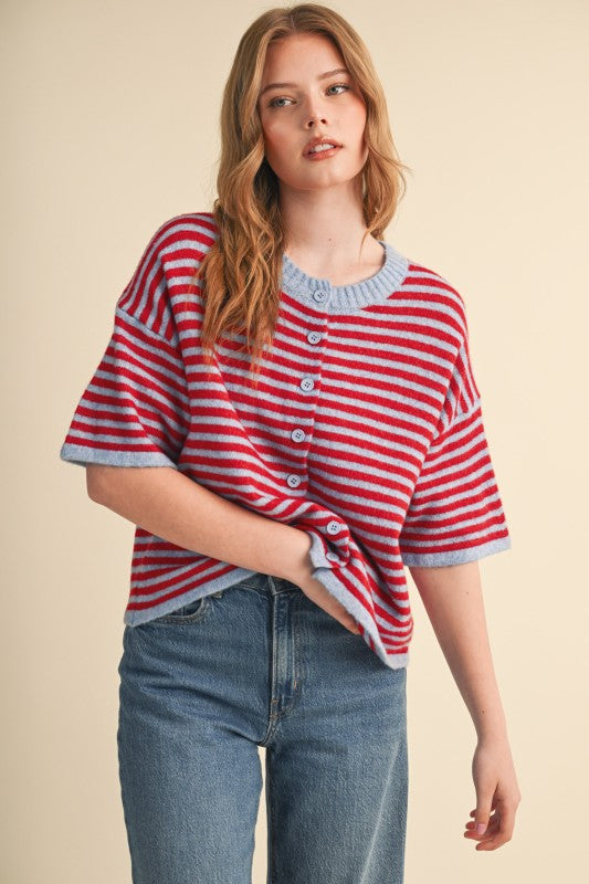 Woman wearing a red and light blue striped short sleeve sweater cardigan with blue jeans.