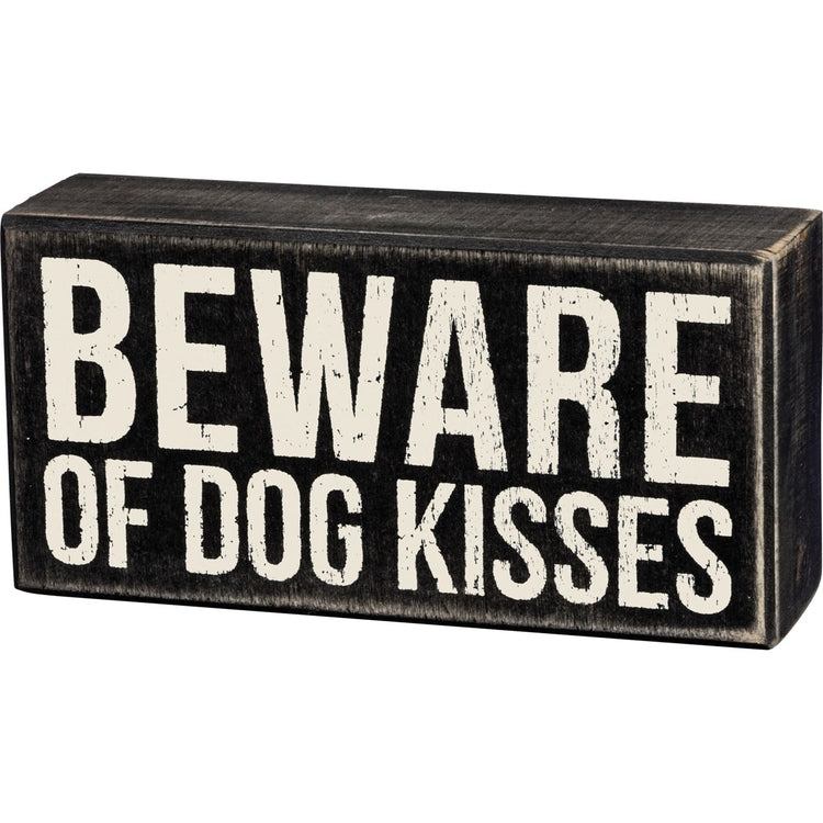 Black wooden box sign with distressed white text reading "BEWARE OF DOG KISSES".