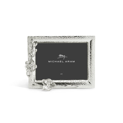 White orchid-patterned nickelplate photo frame holding a 5x7 inch photograph.