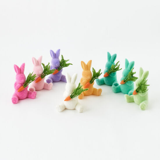 Flocked white bunny figurine holding an orange carrot