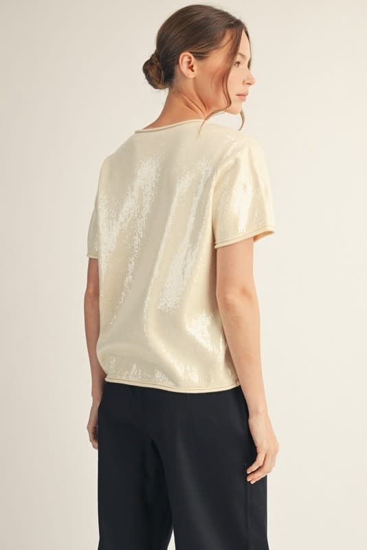 Back view of a beige sequin sweater top with raw cut edge hem.