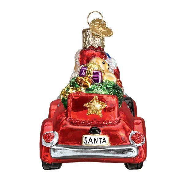 Antique car ornament featuring Santa Claus in a vintage vehicle with red accents.