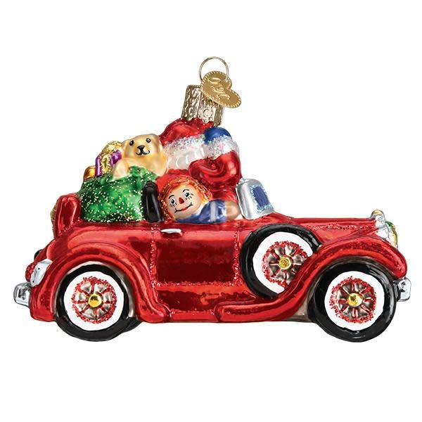 Red antique car ornament with Santa Claus driving through snowy scene.