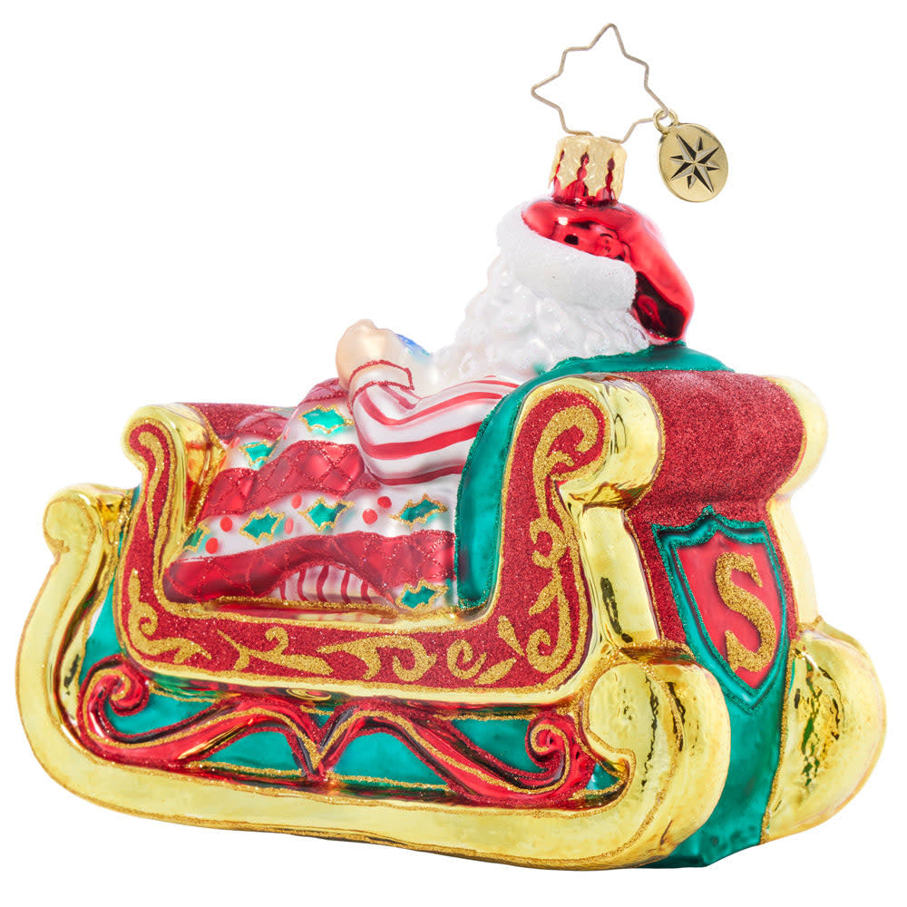 Ceramic Santa figurine sleeping in a sleigh with reindeer.