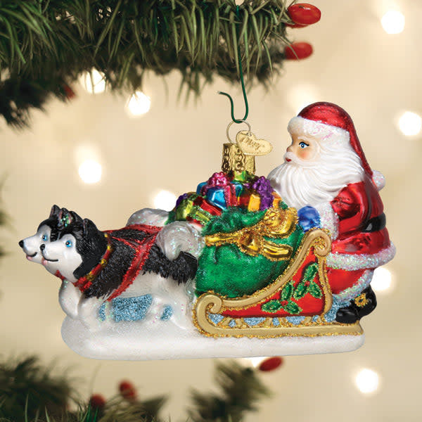 Red Santa sleigh ornament with black sled dogs pulling it against a white background.
