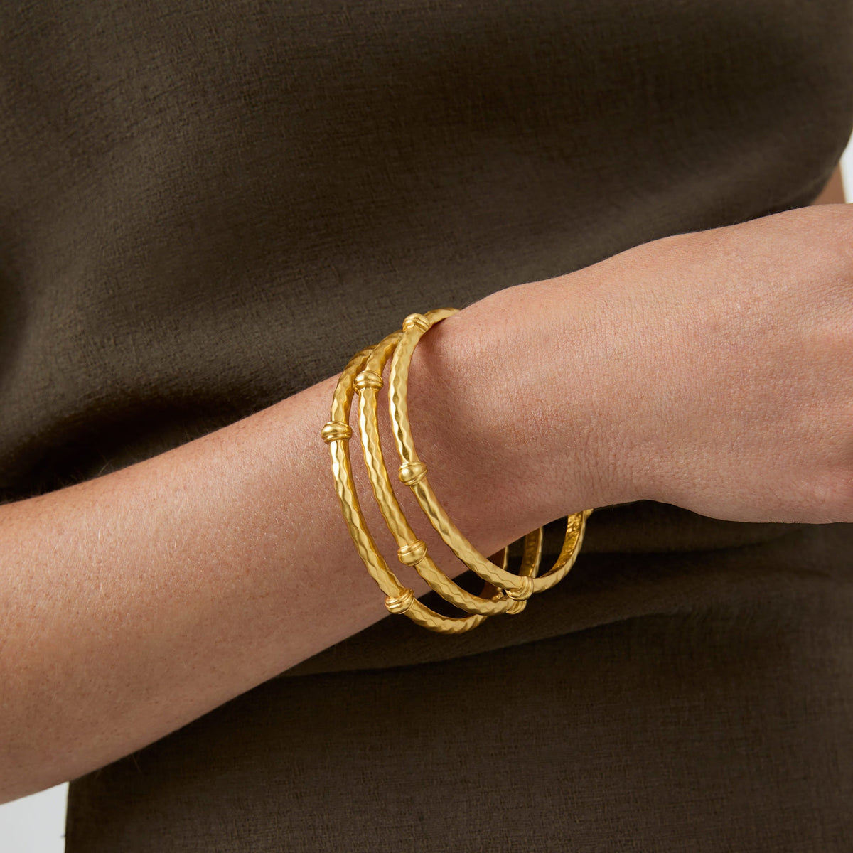 Gilded Savannah bangle featuring diamond hammering texture and decorative stations.
