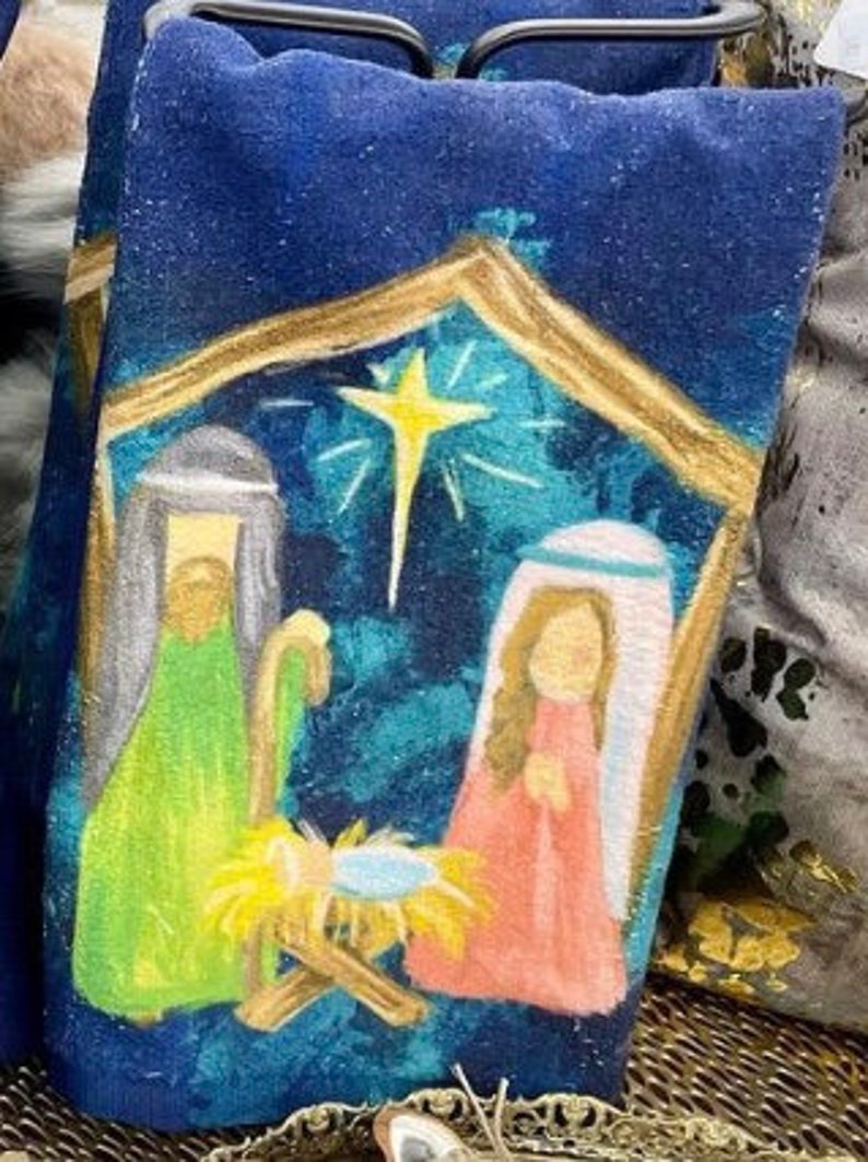 Blue tea towel featuring a hand-painted nativity scene with a star, Joseph, Mary, and baby Jesus.