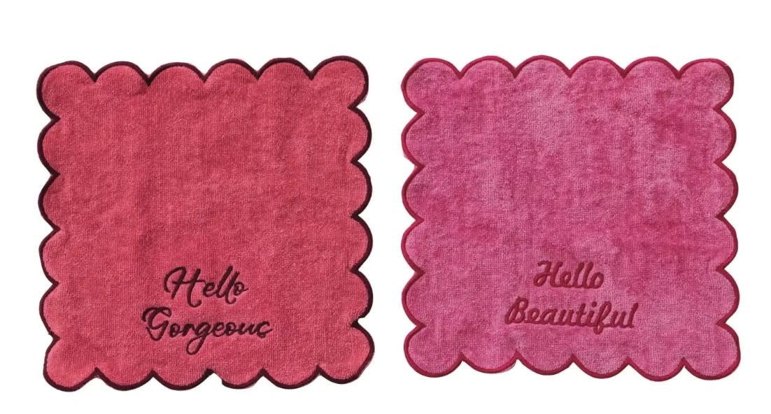 Square cotton bath towel with scalloped edges featuring embroidered 'Hello Gorgeous' text in a soft neutral tone.