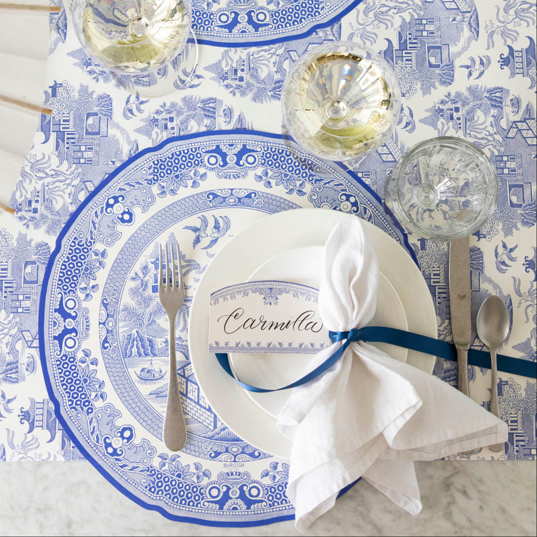 Blue Willow die-cut paper placemat with classic blue floral vine pattern on white background.