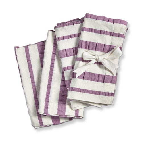 White cotton seersucker napkin with purple stripes and mitered corners.