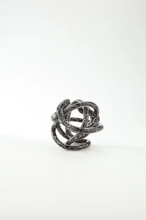 6-inch black glass knot sculpture with white speckled details on a white background.