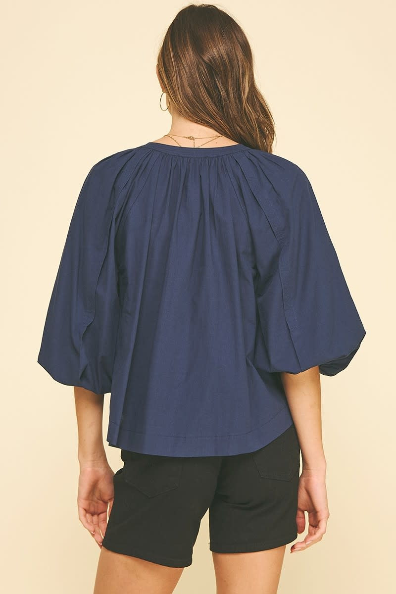 Navy cotton self-tie V-neck blouse with balloon sleeves and elastic cuffs.