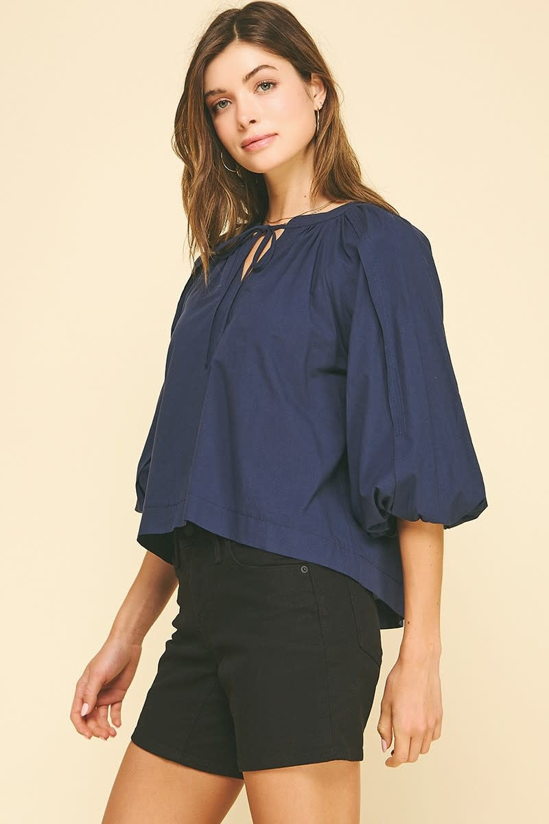 Navy cotton self-tie V-neck blouse with balloon sleeves and elastic cuffs.