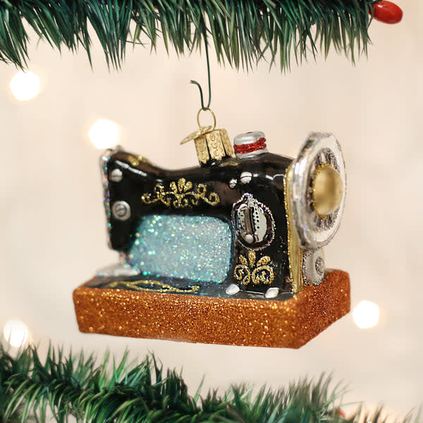 Black metal sewing machine ornament with decorative scrollwork on a white background.