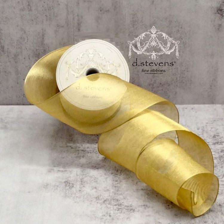 A roll of gold metallic mesh ribbon with a sheer, shimmering texture on a grey background.