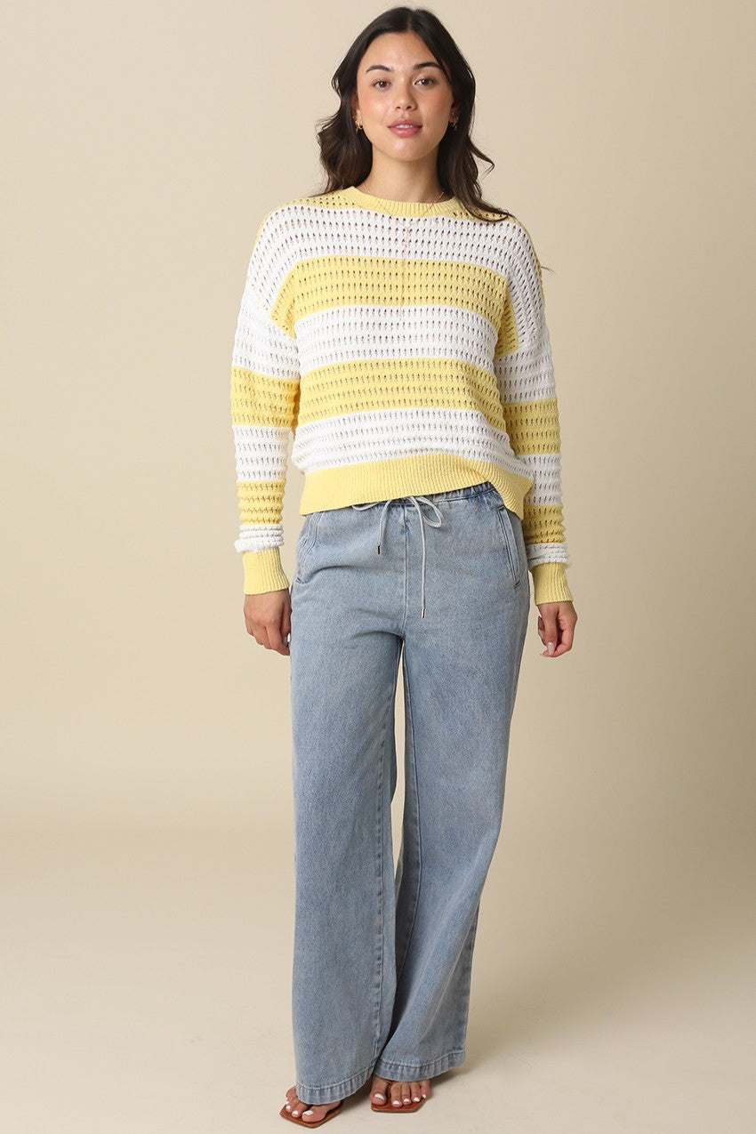 Woman wearing a yellow and white Sadie Mesh Stripe Knit Sweater with light wash denim pants.