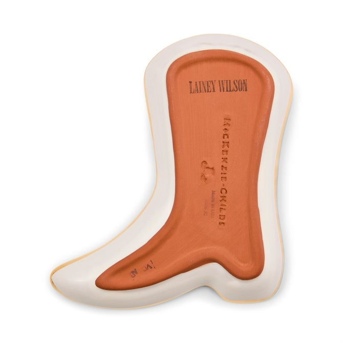 Bottom of a boot-shaped ceramic dish showing Lainey Wilson and MacKenzie-Childs logos on terracotta.