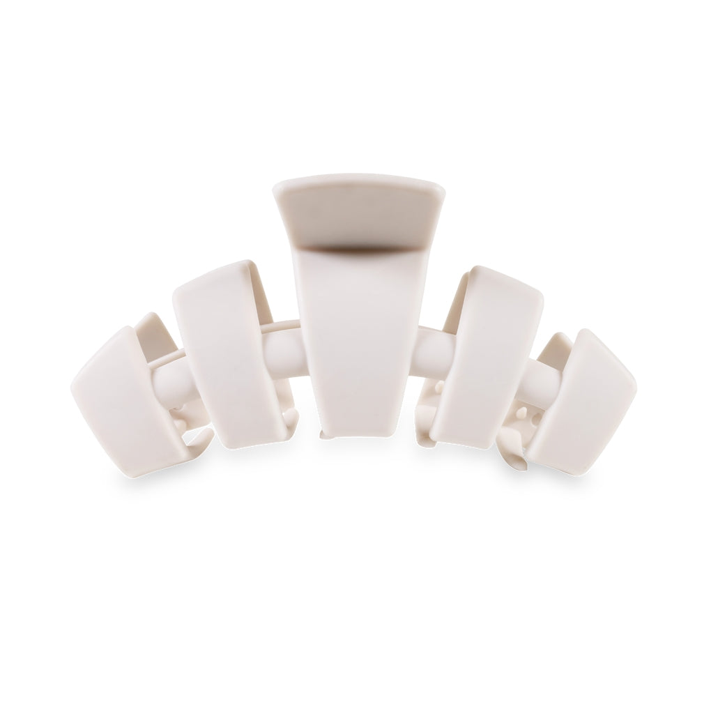 A matte cream-colored medium hair claw clip with a curved, minimalist design.