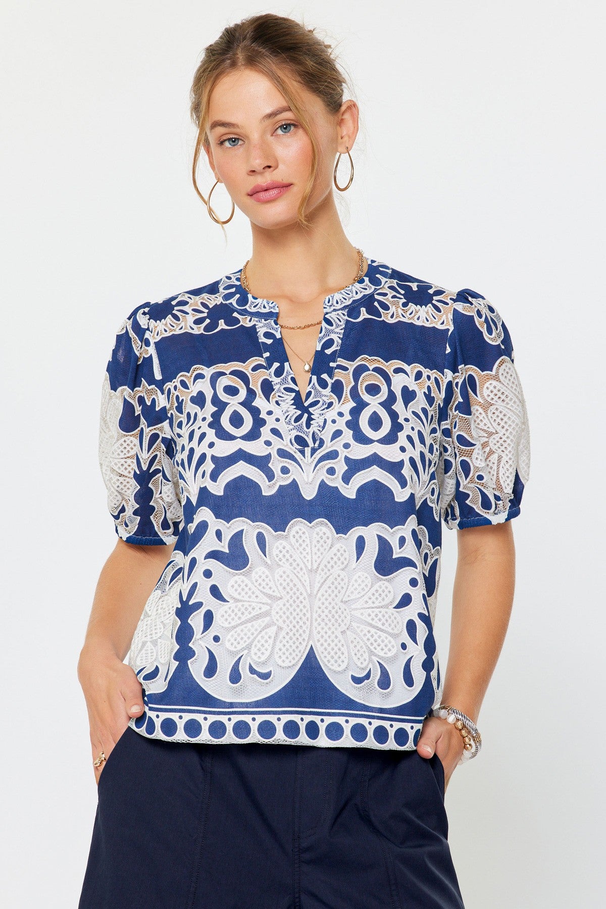 Relaxed fit rayon blouse with all-over lace floral embroidery, split v-neckline, short puff sleeves, and inner cami lining.