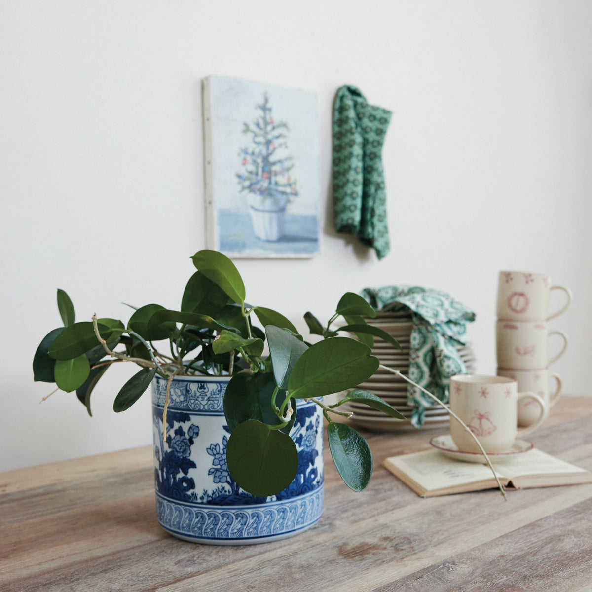 Blue and white stoneware planter with botanical patterns and borders holding a green leafy plant.