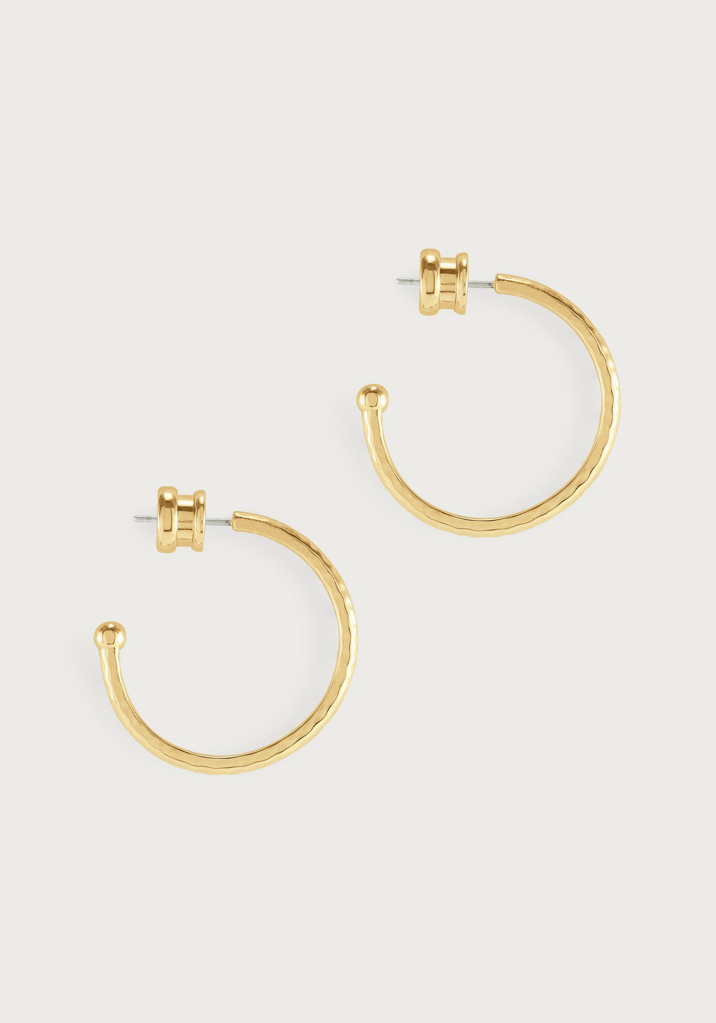 Large 18K gold plated brass hoop earrings with a hammered texture and a small charm detail.