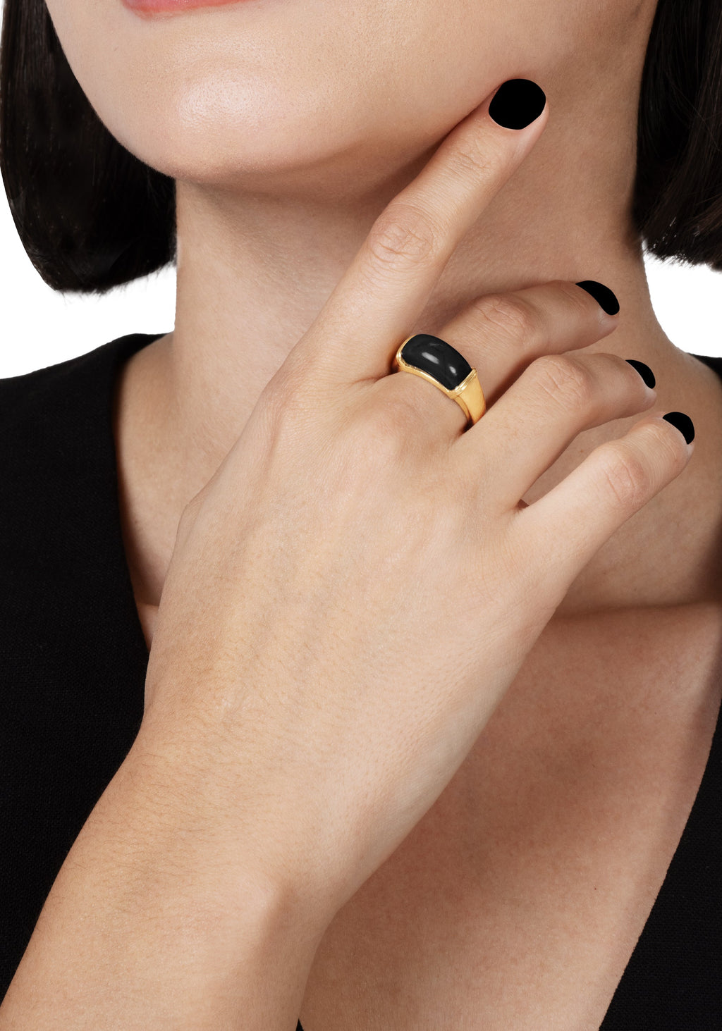 A person wearing the Forza Ring, featuring a gold band set with a polished black onyx stone.