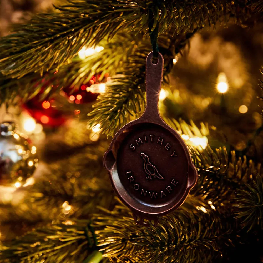 Polished kirksite cast iron skillet ornament with three-hole helper handle and quail logo on green ribbon