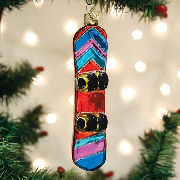 Red snowboard ornament with white bindings standing upright.