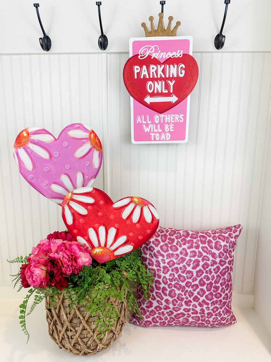 Pink and red daisy heart decorations with a pink leopard print pillow and flowers.