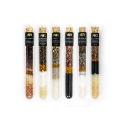 Glass vial containing mineral-rich sea salts, botanicals, clays, essential oils, and bee pollen.
