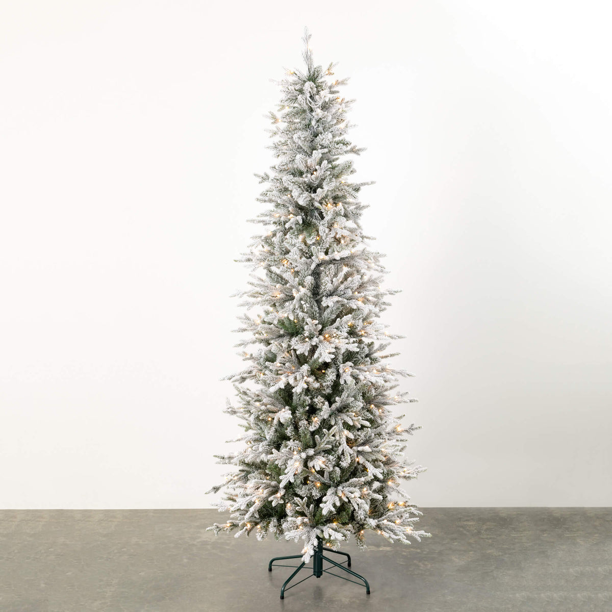 7.5' LED Pencil Flocked Tree with warm white lights on a green metal stand.