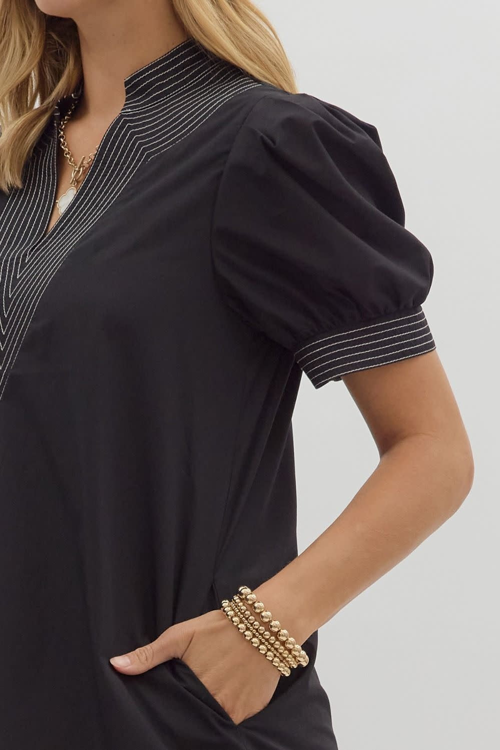 Solid mini dress with puff sleeves, side pockets, contrast stitching at neckband and hem.
