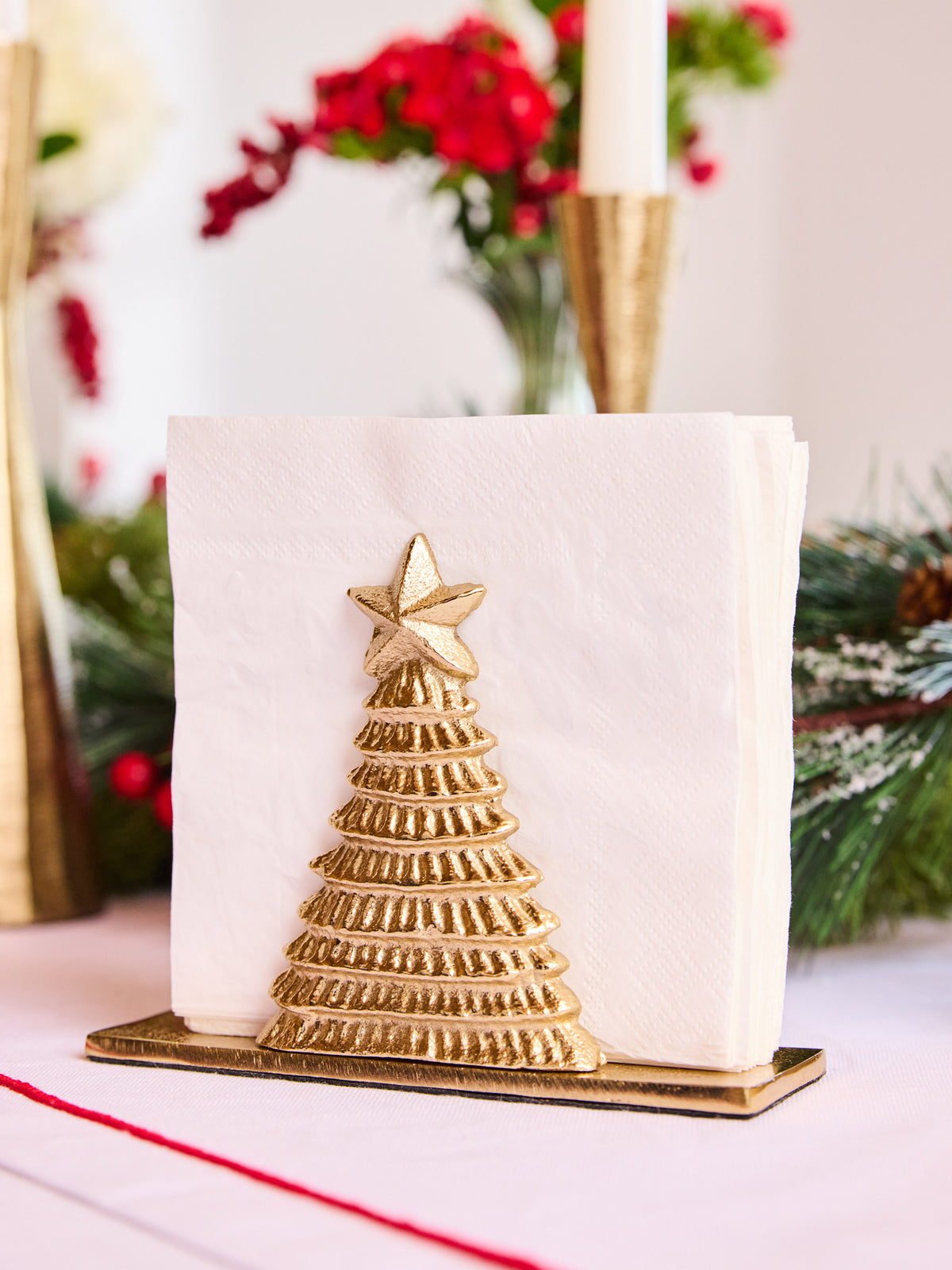 Gold Christmas tree napkin holder with a star on top, holding white napkins.