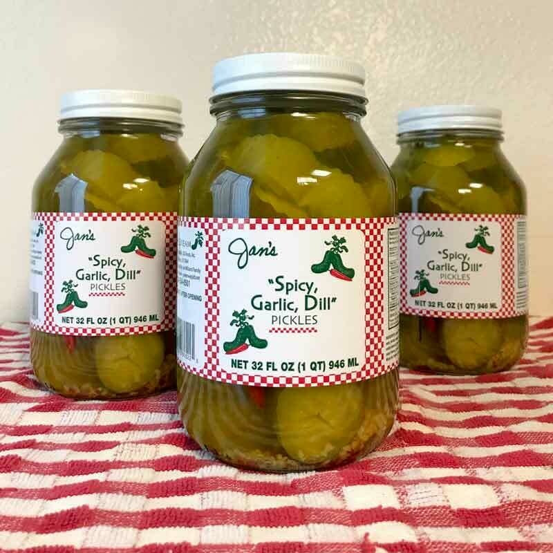 Glass jar containing spicy garlic dill pickles with visible slices submerged in brine.