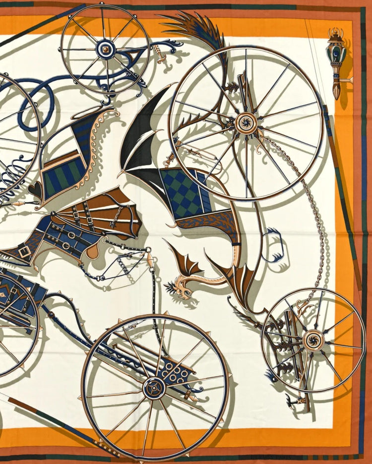 Square silk scarf with a detailed carriage and wheel motif in blue, orange, and gold tones.