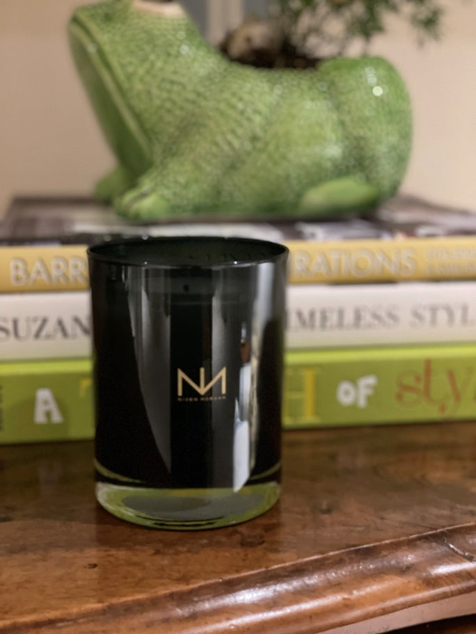 Beach Grass & Dune Candle in a dark navy glass jar with a gold logo on a wooden surface.