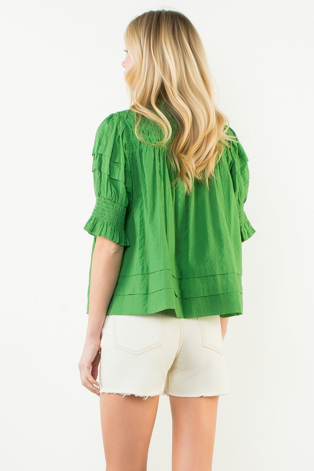 Woman wearing an Alexandra short sleeve crinkle cotton top in light neutral tone with relaxed silhouette.