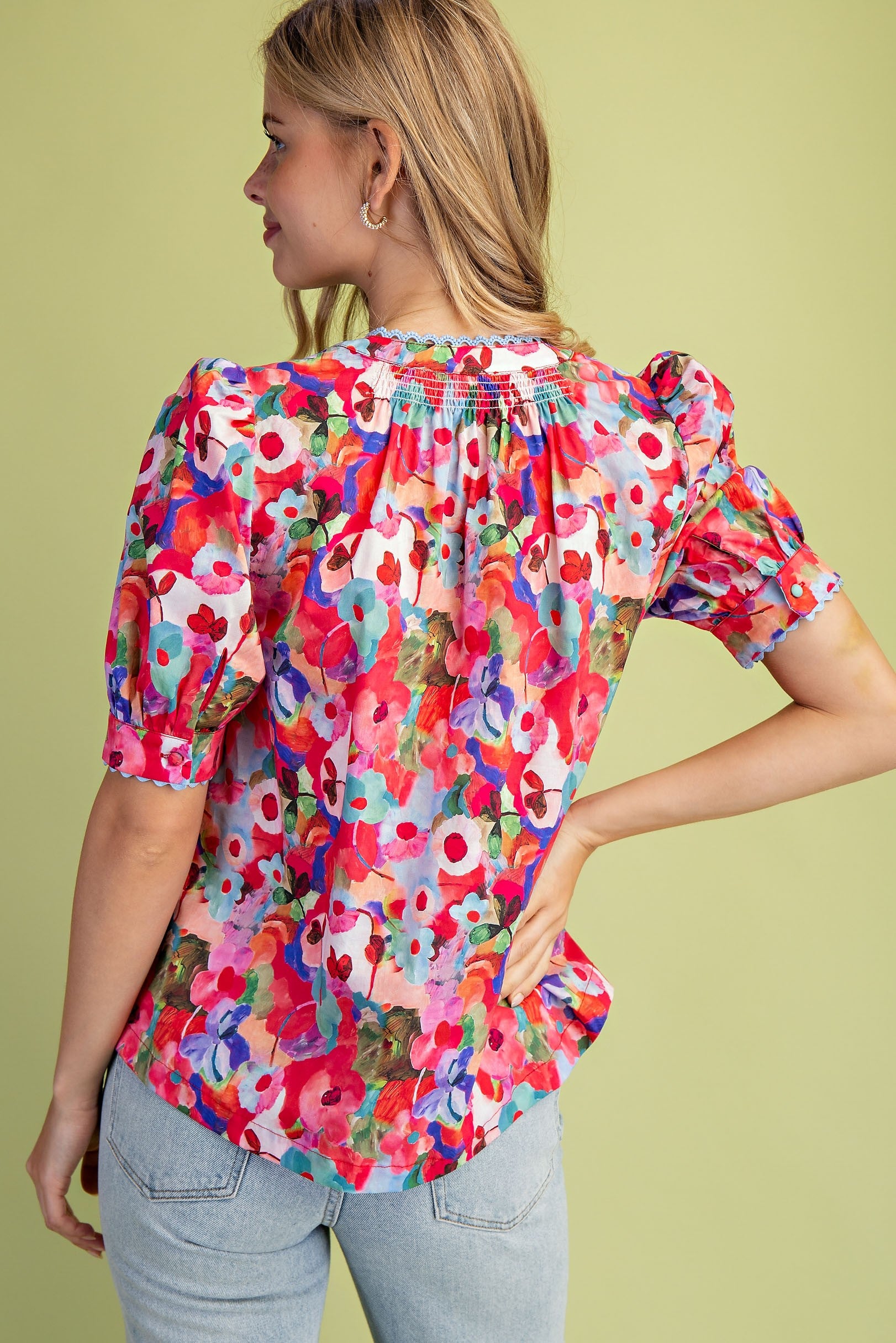 Back view of a woman wearing a Sophia Bold Floral Button Down Blouse with smocking and ric-rac trim.